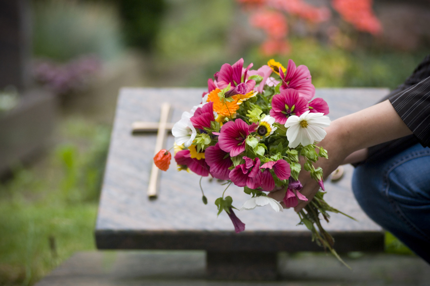 Eine Nahaufnahme eines Blumenstraußes vor einem Grabstein auf einem Friedhof