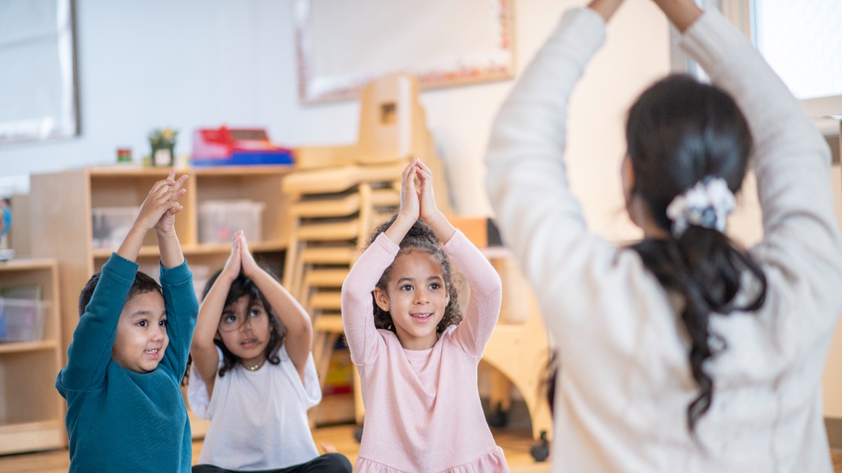 Erzieherin macht mit Kindern Yoga