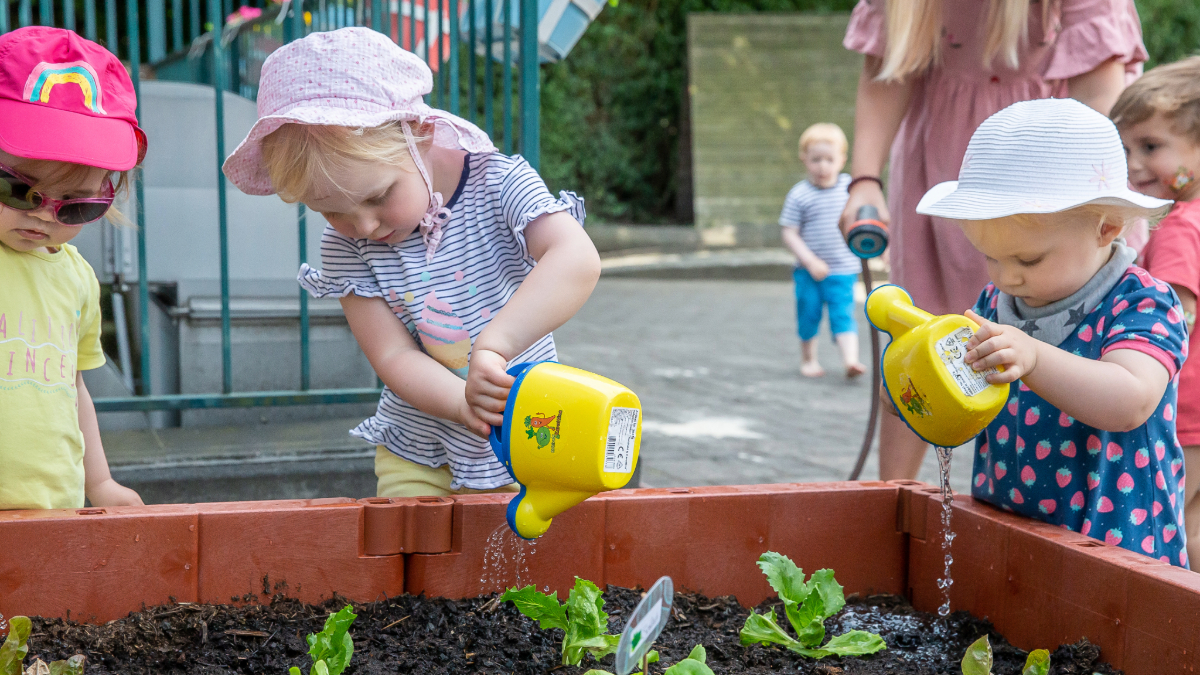 Kleine Kinder gießen ein Hochbeet