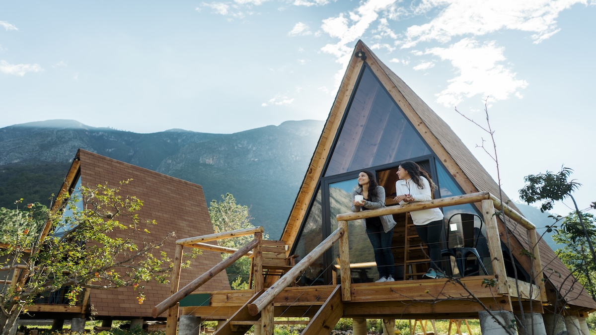 Zwei Freundinnen verbringen gemeinsamen Urlaub und stehen auf der Veranda ihrer Hütte